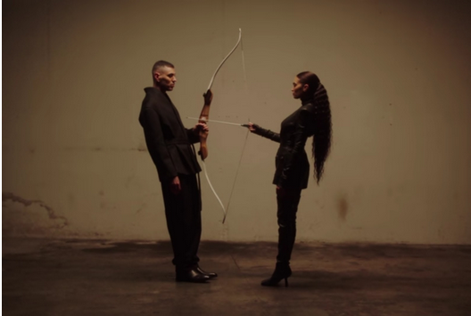 I cantanti Marracash ed Elodie reggono rispettivamente un arco e una freccia.